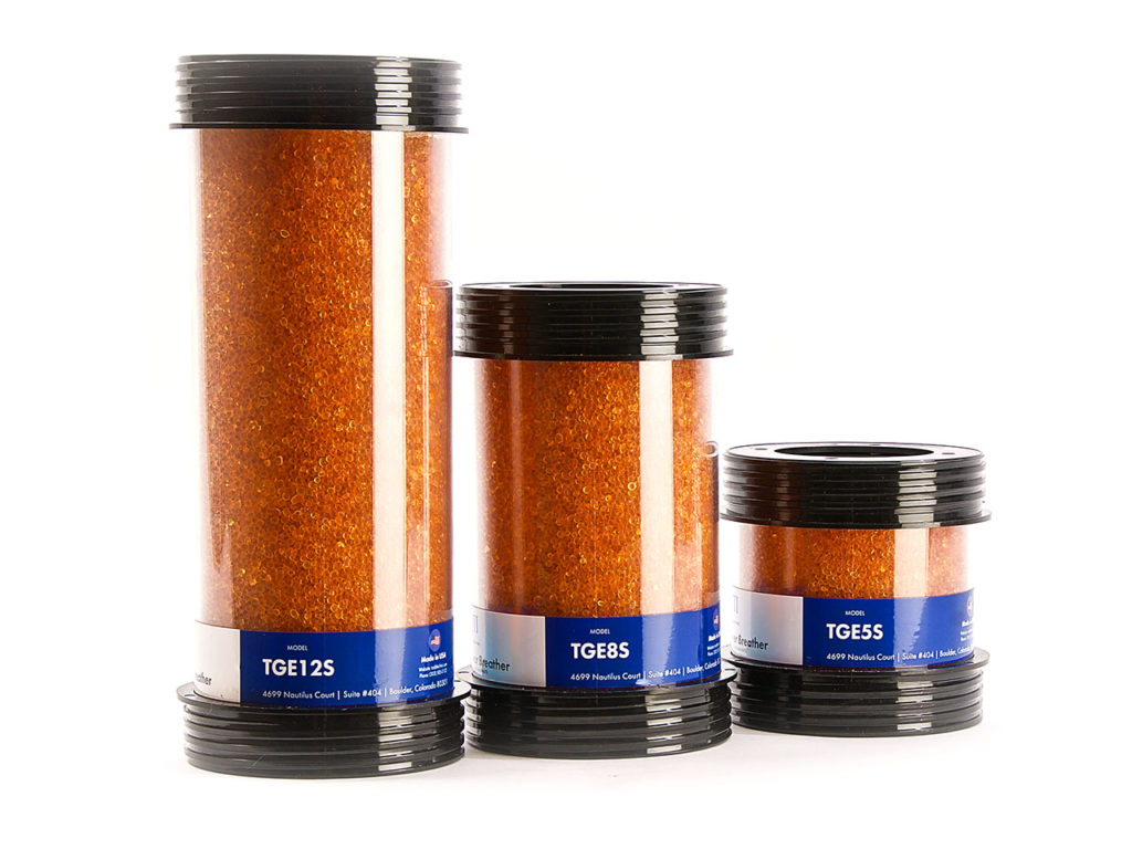 Three transparent desiccant breather models shown together with their housings and visible media